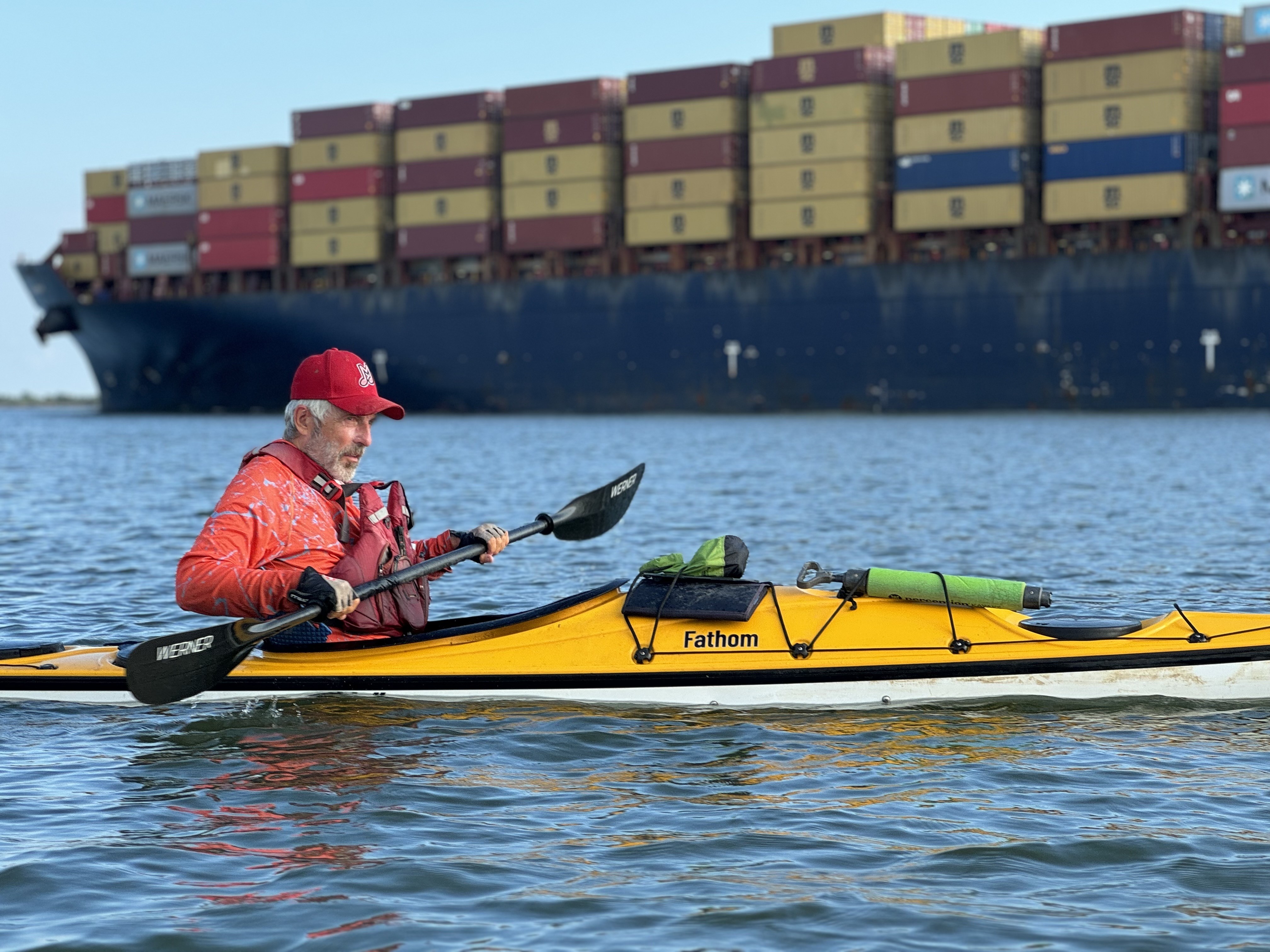 Paul Mellor in a kayak in the water by a cargo ship.